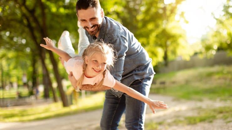 Carefree summer moment Excited father holding his cute daughter on hands playful girl enjoying freedom of flying
