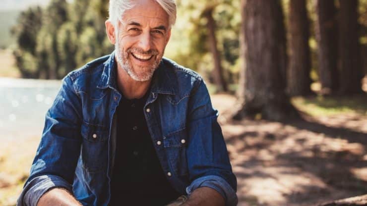 Happy and healthy senior man smiling while enjoying an active lifestyle in nature and outdoor camping