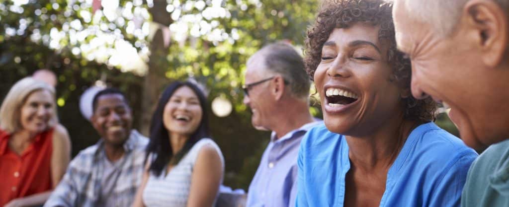 Group Of Mature Friends Socializing In Backyard Together